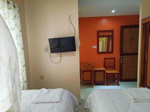 a bedroom with two beds and a tv on the wall at Balqies Homestay Syariah Makassar Mitra RedDoorz in Makassar