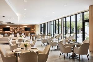 a restaurant with tables and chairs and windows at AC Hotel By Marriott Dallas By The Galleria in Dallas