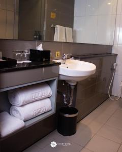een badkamer met een wastafel, een spiegel en handdoeken bij Ivory Hotel Bandung in Bandung