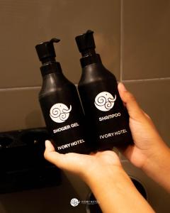 una persona con dos botellas negras de detergente para ropa en Ivory Hotel Bandung en Bandung
