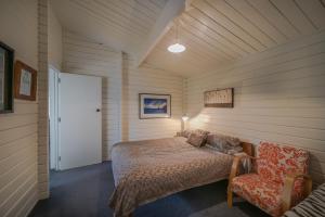 a bedroom with a bed and a chair in a room at Birdsong Bliss - Takamatua Holiday Home in Takamatua Bay