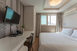 ein Hotelzimmer mit einem Bett und einem Flachbild-TV in der Unterkunft Staywell Hotel in Busan
