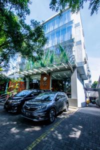dois carros estacionados em frente a um edifício em Ivory Hotel Bandung em Bandung