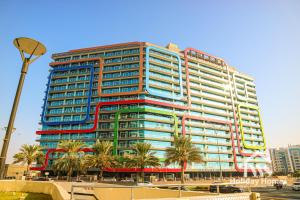 a tall building with red and blue windows and palm trees at The Urban Oasis - Serenity in Dubai