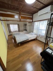 a bedroom with two beds and a wooden floor at Japanese Onlyの古民家-Villa Ukishima- in Naha