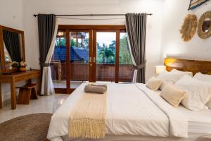 a bedroom with a large white bed with a window at Villa Innerbloom stylish 2BR with large pool & garden in Canggu