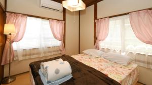 a bedroom with a bed with pink curtains and a window at Japanese Onlyの古民家-Villa Ukishima- in Naha +13 photos