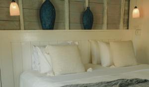 a bedroom with a bed with pillows and vases on the wall at Sandy Bay in Nusa Lembongan