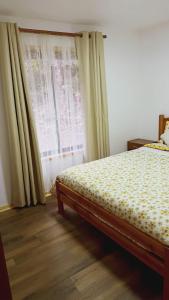 Schlafzimmer mit einem Bett und einem Fenster mit Vorhängen in der Unterkunft Cabaña en Coñaripe Sector Termas Geométricas in Coñaripe