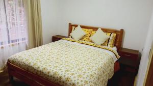 ein Schlafzimmer mit einem Bett mit einer gelben und weißen Bettdecke in der Unterkunft Cabaña en Coñaripe Sector Termas Geométricas in Coñaripe