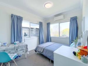 1 dormitorio con 1 cama con cortinas azules y escritorio en Cozy 4B3B home w parking WIFI @Clayton, en Clayton North