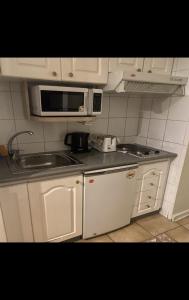 una pequeña cocina con armarios blancos y microondas en Luigi's Apart Hotel, en Santiago