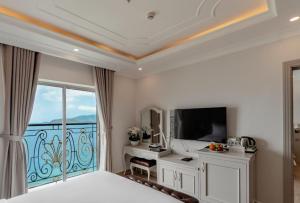MerPerle Beach Hotel في نها ترانغ: غرفة نوم بسرير وتلفزيون وشرفة