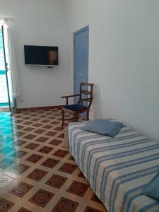 1 dormitorio con 1 cama, 1 silla y TV en Dan Ravello, en Ravello