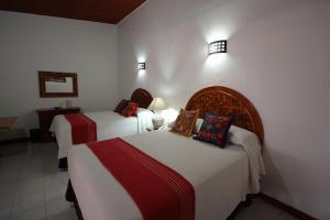 Habitación de hotel con 2 camas con sábanas rojas y blancas en Hotel Anua Oaxaca, en Oaxaca City