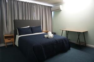 ein Schlafzimmer mit einem Bett mit einer blauen Decke und einem Tisch in der Unterkunft Warners Bay Hotel in Warners Bay