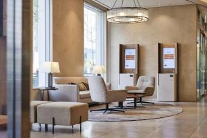 a living room with chairs and tables and windows at LOTTE CITY HOTEL Ulsan in Ulsan