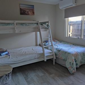 1 dormitorio con 2 literas y mesa en Holiday Home in Papamoa, en Tauranga