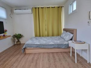 a bedroom with a bed and a desk and a television at Cozy House & Tour in Jeju