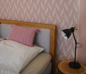 Una cama con una almohada rosa y una lámpara sobre una mesa en Ferienwohnung Nr 4, en Litzendorf