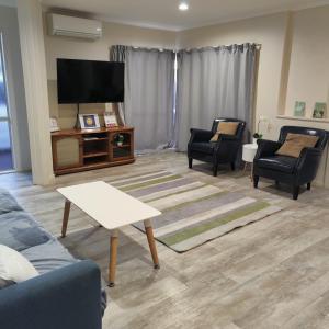 sala de estar con muebles y TV de pantalla plana en Holiday Home in Papamoa, en Tauranga