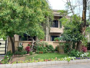 a garden in front of a house with flowers at Riviera Courtyard Guest House Islamabad in Islamabad