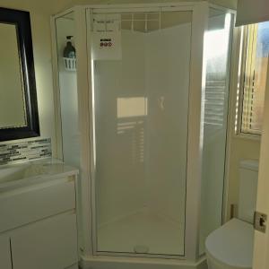 a glass shower in a bathroom with a toilet at Holiday Home in Papamoa in Tauranga