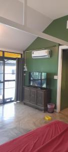 uma sala de estar com uma televisão de ecrã plano numa parede verde em บ้านลูกจัน Bann Lookjan Trat em Trat