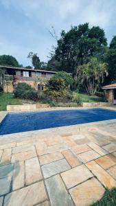 a stone patio with a pool in front of a house at Chale em Atibaia in Atibaia