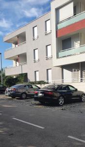 zwei Autos auf einem Parkplatz vor einem Gebäude geparkt in der Unterkunft Apartman Zaravecchia in Biograd na Moru