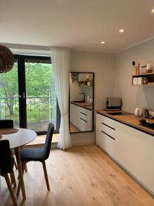 une cuisine avec des placards blancs, une table et une fenêtre dans l'établissement Seaside apartment Albatross, 16, à Ķesterciems