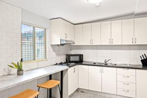 a white kitchen with a sink and a microwave at Signature Double Room in Auburn in Sydney