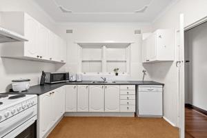 a white kitchen with white cabinets and a microwave at Signature Queen Room in Auburn in Sydney