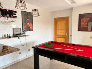 una mesa de ping pong en una habitación con una mesa de billar rojo en BoBo House Airport en Nouaceur