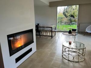 a living room with a fireplace and a table at La Lumineuse du Moulin in Saint-Germain-sur-Bresle