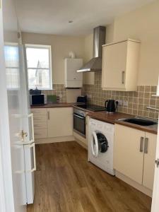 a kitchen with white cabinets and a washing machine at 7A Murray Street in Duns