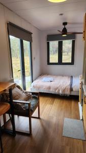 a bedroom with a bed and a chair and a window at Tiny Home - Redbird in Hartley