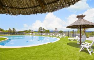 a pool with chairs and an umbrella and grass at 2 Bedroom Awesome Home In Grospierres in Grospierres +19 photos