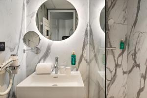 een badkamer met een wastafel en een douche met een spiegel bij Hôtel & Spa Le Maury, Vannes, The Originals Boutique in Vannes