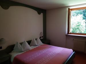 a bedroom with a bed with a red blanket and a window at Albergo Scoiattolo in Tret