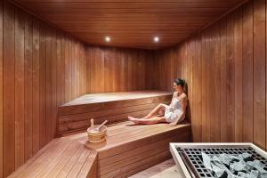 una mujer está sentada en una sauna en Hôtel & Spa Le Maury, Vannes, The Originals Boutique, en Vannes