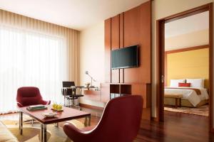 a hotel room with a bed and a living room with a table at Courtyard by Marriott Kochi Airport in Nedumbassery