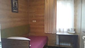 a room with a purple bed and a table and a window at Sapar Budget Hotel in Shymkent