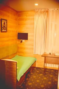 Habitación pequeña con cama verde y escritorio. en Sapar Budget Hotel en Shymkent