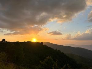 a sunset on top of a hill with the sun setting at Wincliff Orchard Resort in Mukteshwar