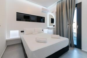 a white bedroom with a white bed and a tv at SithoniaRS Luxury 1st Floor Apartment With SeaView in Neos Marmaras