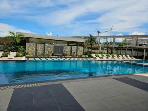 a large swimming pool with lounge chairs and a building at JETS'3 Condo Rentals in Bacolod