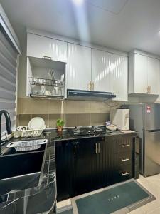 La cuisine est équipée de placards blancs et d'un réfrigérateur en acier inoxydable. dans l'établissement Modern Stylish Apartment (Seaview) near KTCC Mall., à Kuala Terengganu