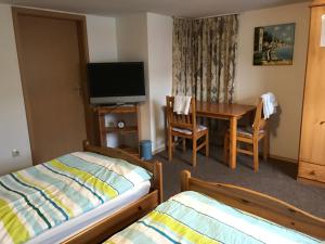 a bedroom with two beds and a table and a television at Pension Grüner Baum 