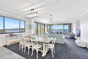 a dining room and living room with a table and chairs at Water's Edge Apartment 2 absolute waterfront at Fishing Point on Lake Macquarie in Fishing Point